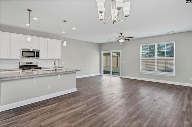 kitchen with sink, dark wood-type flooring, pendant lighting, white cabinets, and appliances with stainless steel finishes