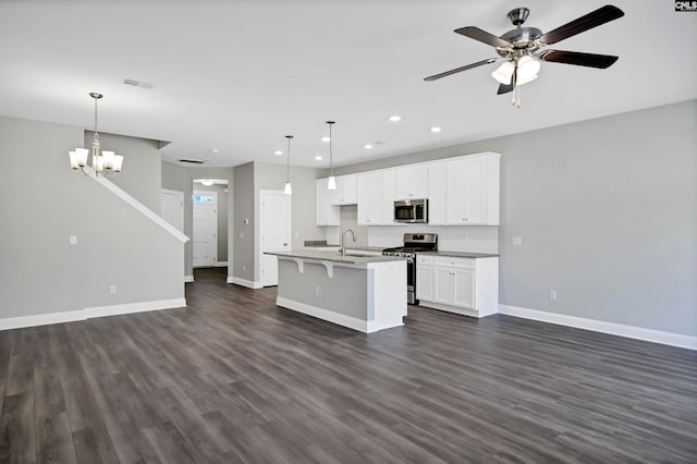 kitchen with pendant lighting, a center island with sink, dark hardwood / wood-style floors, white cabinetry, and stainless steel appliances