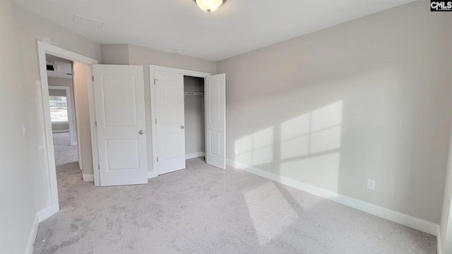 unfurnished bedroom with light colored carpet and a closet