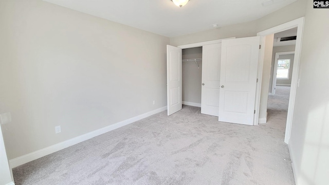 unfurnished bedroom with light colored carpet and a closet