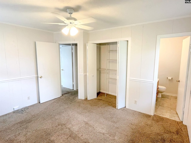 unfurnished bedroom featuring ensuite bath, ceiling fan, light colored carpet, and ornamental molding