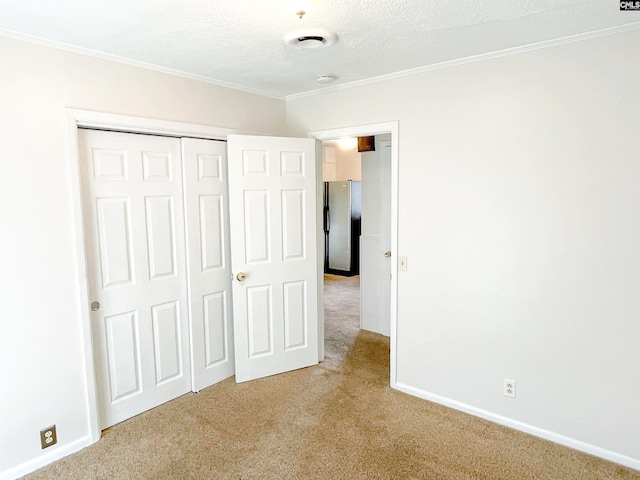 unfurnished bedroom featuring crown molding, stainless steel fridge, a textured ceiling, light carpet, and a closet