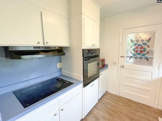 kitchen with black appliances, light wood-type flooring, white cabinetry, and range hood