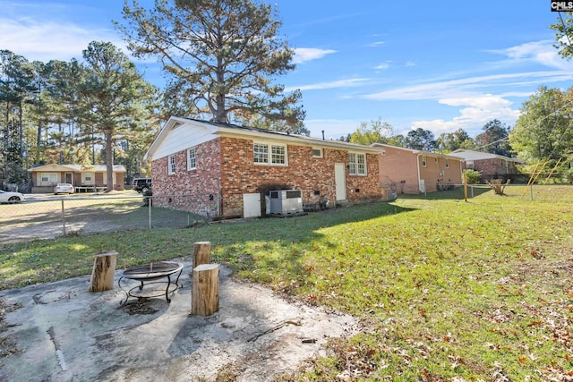 rear view of property featuring a yard and an outdoor fire pit