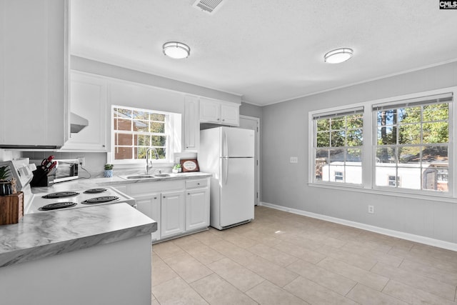 kitchen with white fridge, white cabinetry, a healthy amount of sunlight, and sink