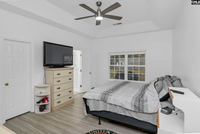 bedroom featuring a raised ceiling, ceiling fan, and hardwood / wood-style floors