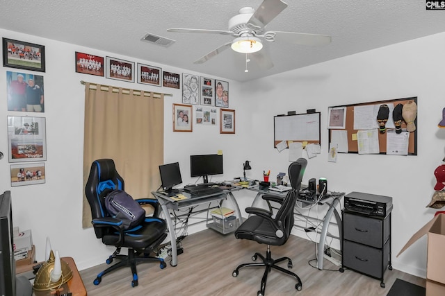 home office with a textured ceiling, light hardwood / wood-style floors, and ceiling fan