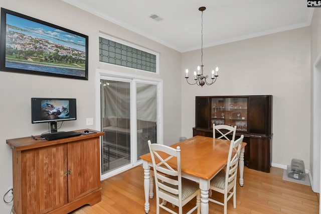 dining room with crown molding, light hardwood / wood-style flooring, and an inviting chandelier