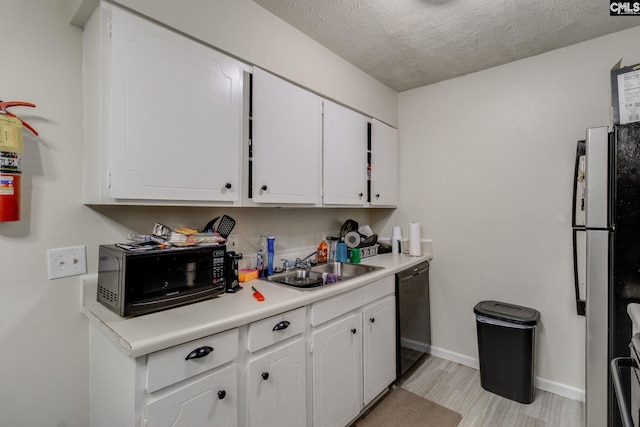 kitchen featuring sink, a textured ceiling, white cabinets, black appliances, and light wood-type flooring