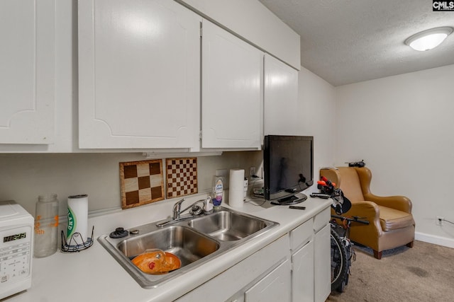 kitchen featuring white cabinets, a textured ceiling, light colored carpet, and sink