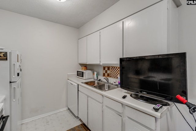 kitchen featuring a textured ceiling, white cabinetry, sink, and white appliances