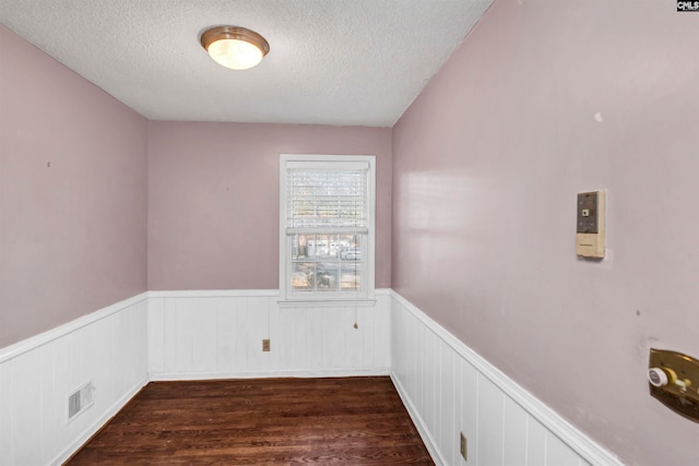 empty room featuring dark wood-type flooring and a textured ceiling