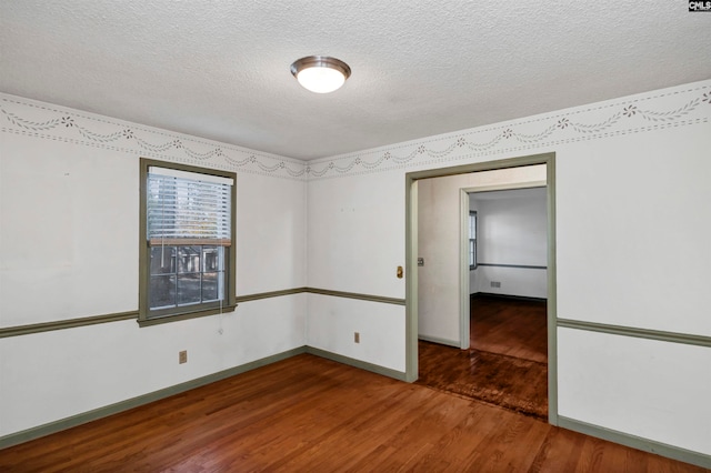 empty room with dark hardwood / wood-style flooring and a textured ceiling