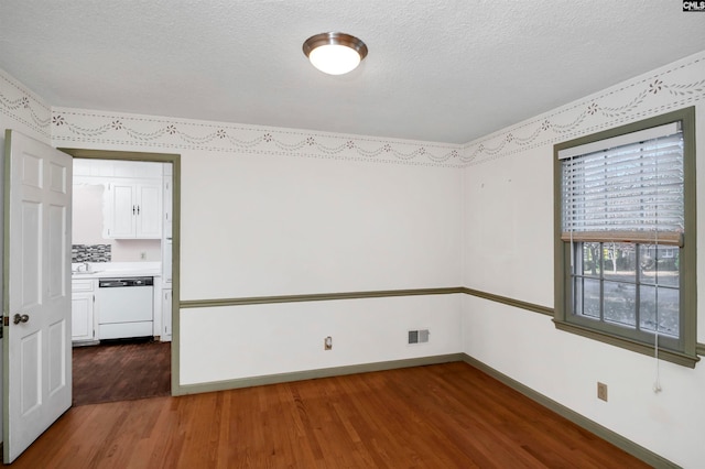 empty room with sink, dark wood-type flooring, and a textured ceiling