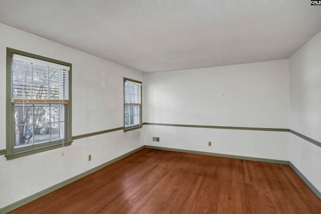 spare room with a healthy amount of sunlight, a textured ceiling, and wood-type flooring