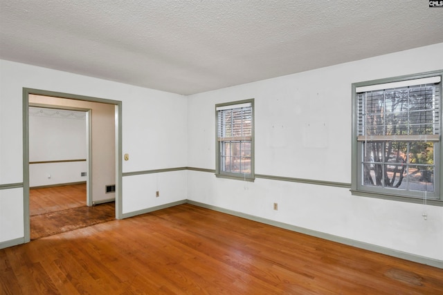 spare room featuring hardwood / wood-style floors and a textured ceiling