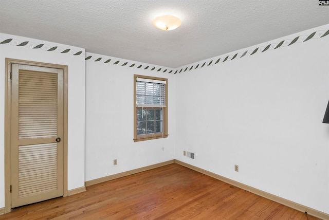 spare room featuring hardwood / wood-style floors and a textured ceiling