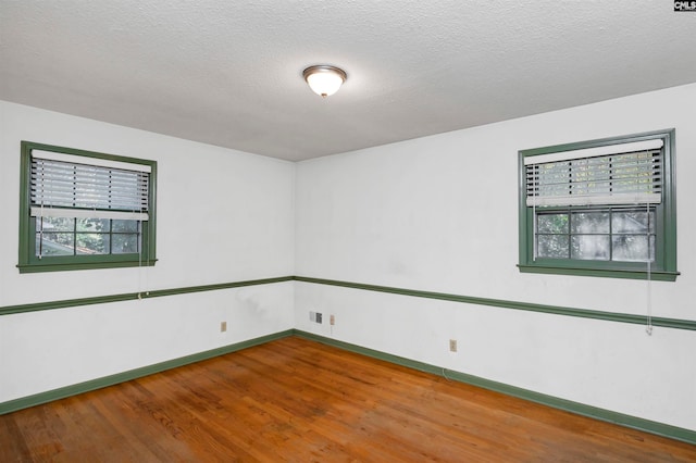 unfurnished room with wood-type flooring and a textured ceiling