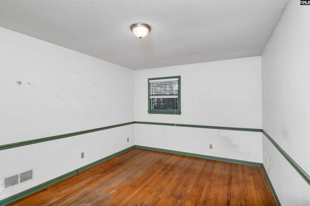 empty room featuring wood-type flooring and a textured ceiling