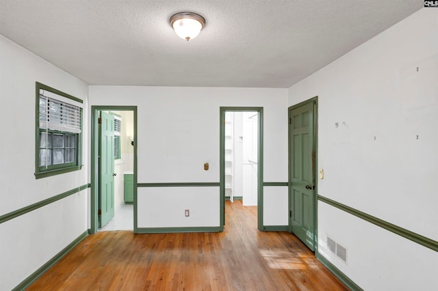 unfurnished room featuring a textured ceiling and light wood-type flooring