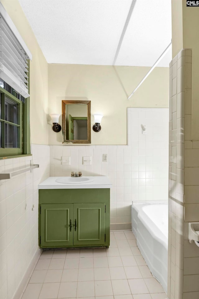 bathroom with tile patterned flooring, a washtub, tile walls, and vanity