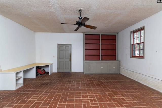 interior space with ceiling fan and a textured ceiling