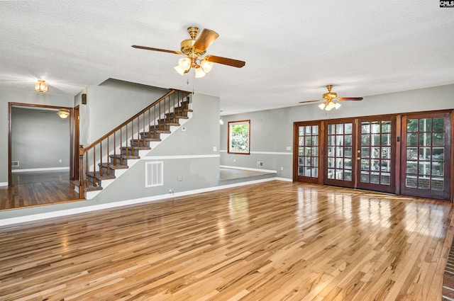 unfurnished living room with ceiling fan, wood-type flooring, a textured ceiling, and french doors