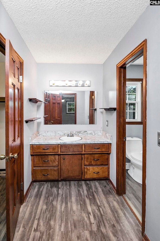 bathroom with vanity, wood-type flooring, a textured ceiling, and toilet