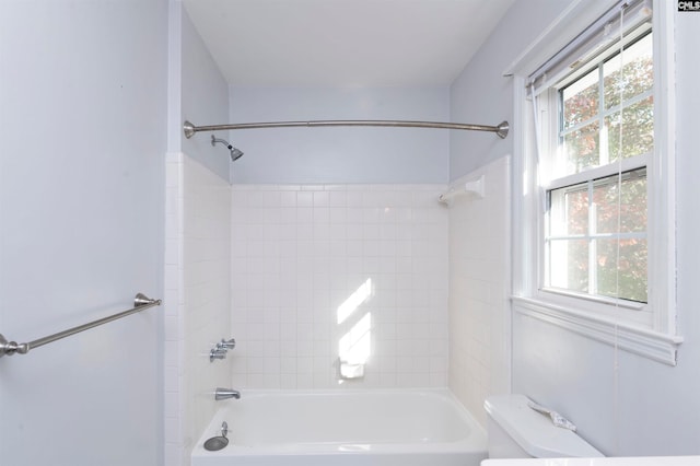 bathroom featuring toilet and tiled shower / bath