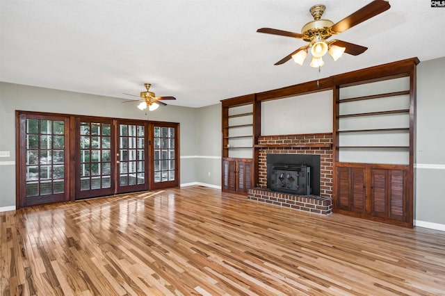 unfurnished living room featuring ceiling fan, a fireplace, light hardwood / wood-style floors, and a textured ceiling