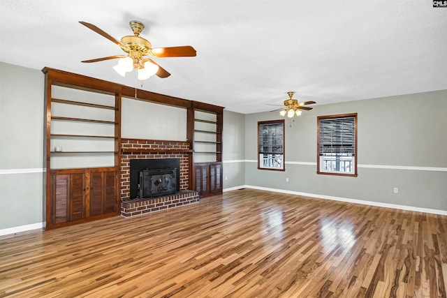 unfurnished living room featuring a brick fireplace, ceiling fan, a textured ceiling, and hardwood / wood-style flooring