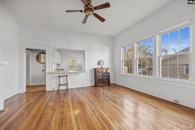 unfurnished living room featuring ceiling fan, sink, ornamental molding, and light wood-type flooring