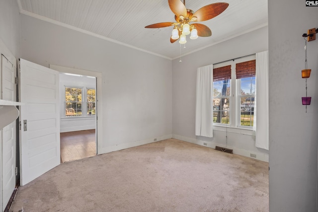 empty room featuring ceiling fan, light colored carpet, ornamental molding, and a wealth of natural light