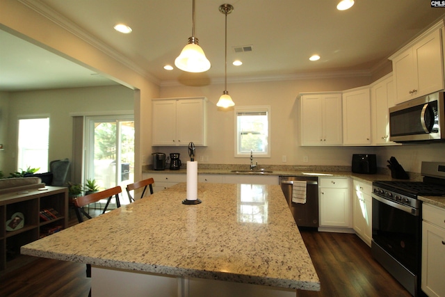 kitchen with light stone countertops, sink, a center island, white cabinets, and appliances with stainless steel finishes