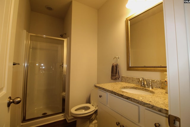 bathroom featuring vanity, a shower with shower door, and toilet