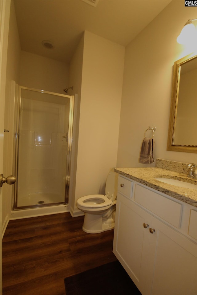 bathroom with hardwood / wood-style flooring, vanity, toilet, and an enclosed shower