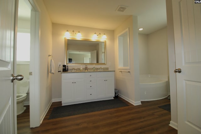 bathroom with a bathing tub, vanity, toilet, and hardwood / wood-style floors