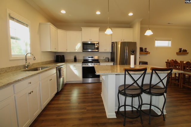 kitchen with pendant lighting, a breakfast bar, sink, appliances with stainless steel finishes, and white cabinetry