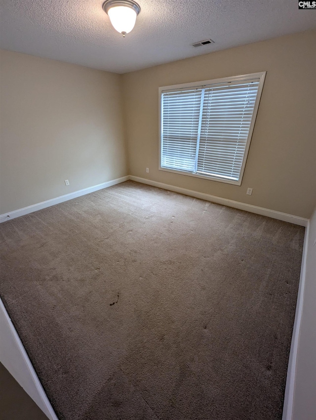 carpeted empty room featuring a textured ceiling