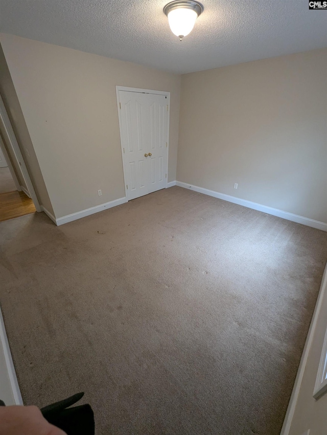 empty room with carpet floors and a textured ceiling