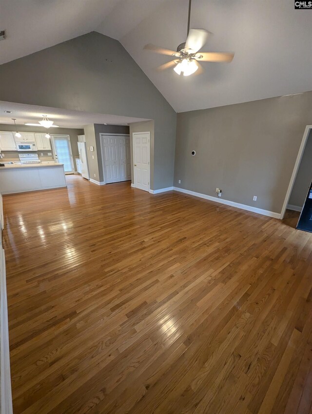 unfurnished living room with hardwood / wood-style floors, ceiling fan, and vaulted ceiling