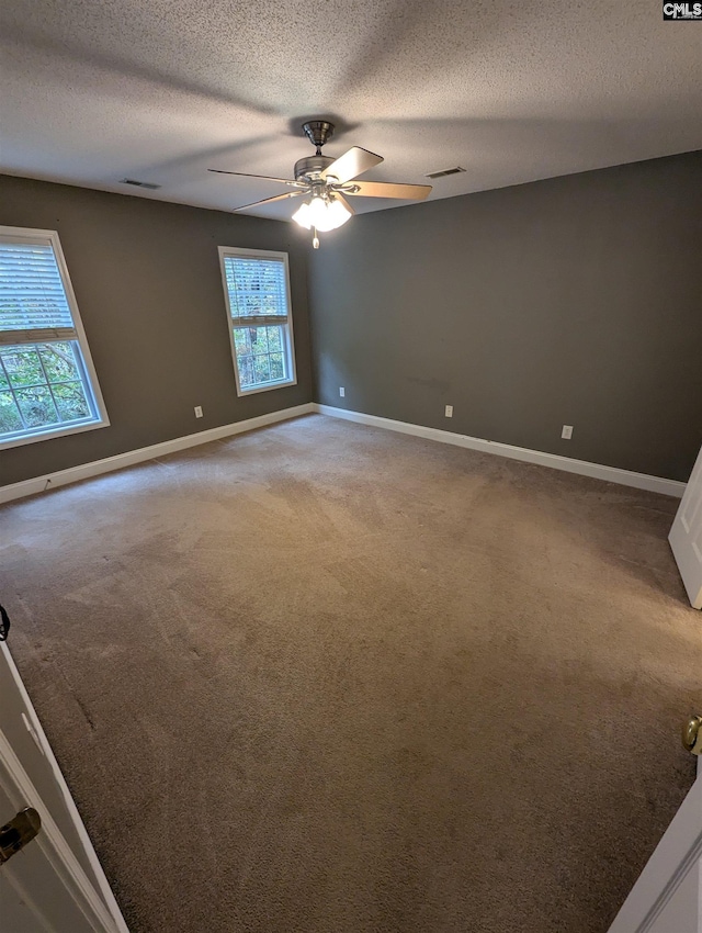 carpeted spare room featuring ceiling fan and a textured ceiling