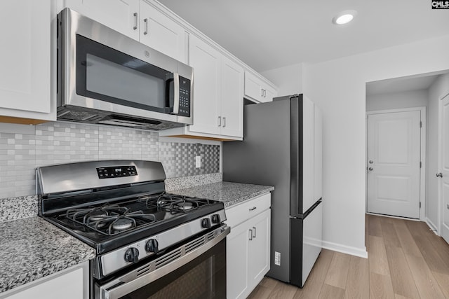 kitchen featuring white cabinets, appliances with stainless steel finishes, and light stone counters