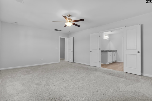 unfurnished bedroom with ceiling fan, ensuite bathroom, and light carpet