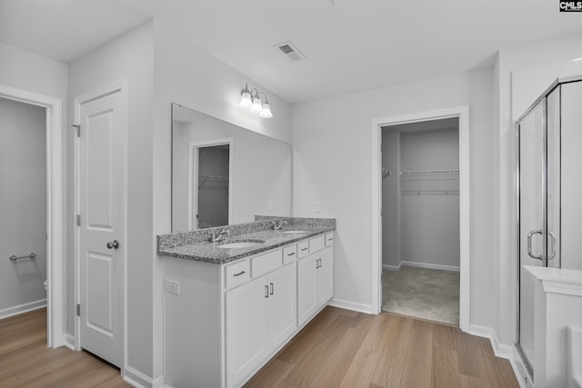 bathroom with hardwood / wood-style flooring, vanity, and a shower with shower door