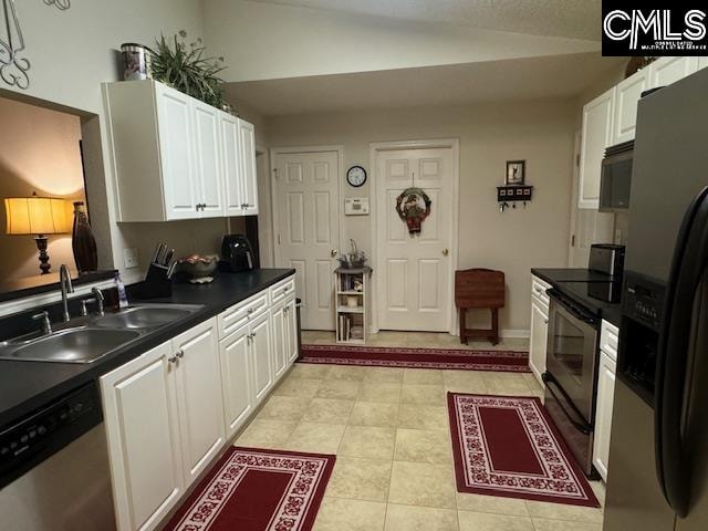 kitchen with sink, vaulted ceiling, light tile patterned floors, white cabinetry, and stainless steel appliances