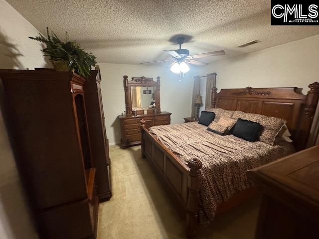 carpeted bedroom with ceiling fan and a textured ceiling