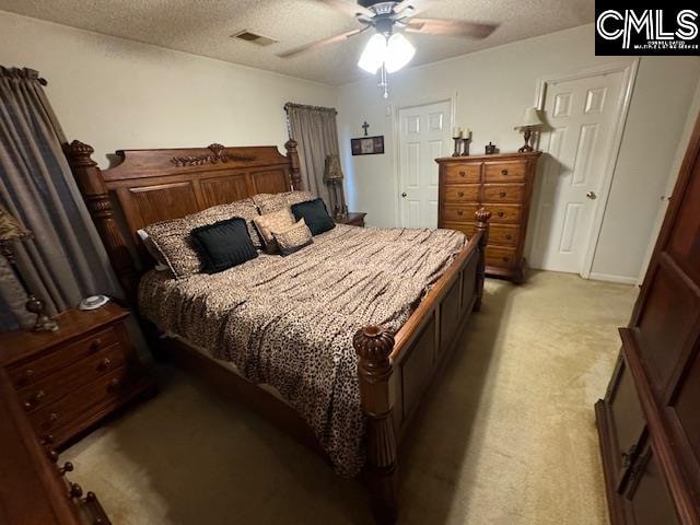 bedroom featuring a textured ceiling, light colored carpet, and ceiling fan