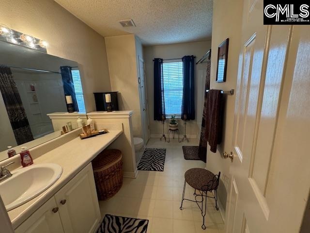 bathroom with a shower with curtain, toilet, and a textured ceiling