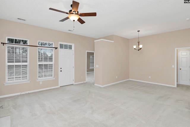 carpeted spare room featuring ceiling fan with notable chandelier